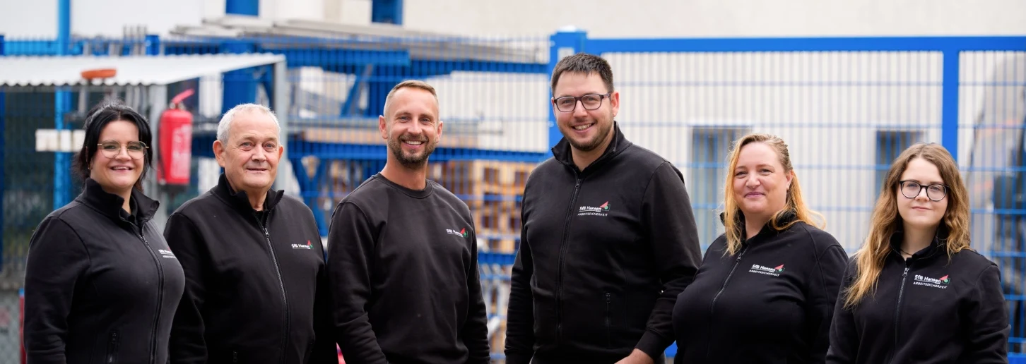 Das Team der SfB Hansen GmbH in schwarzer Arbeitskleidung mit Firmenlogo